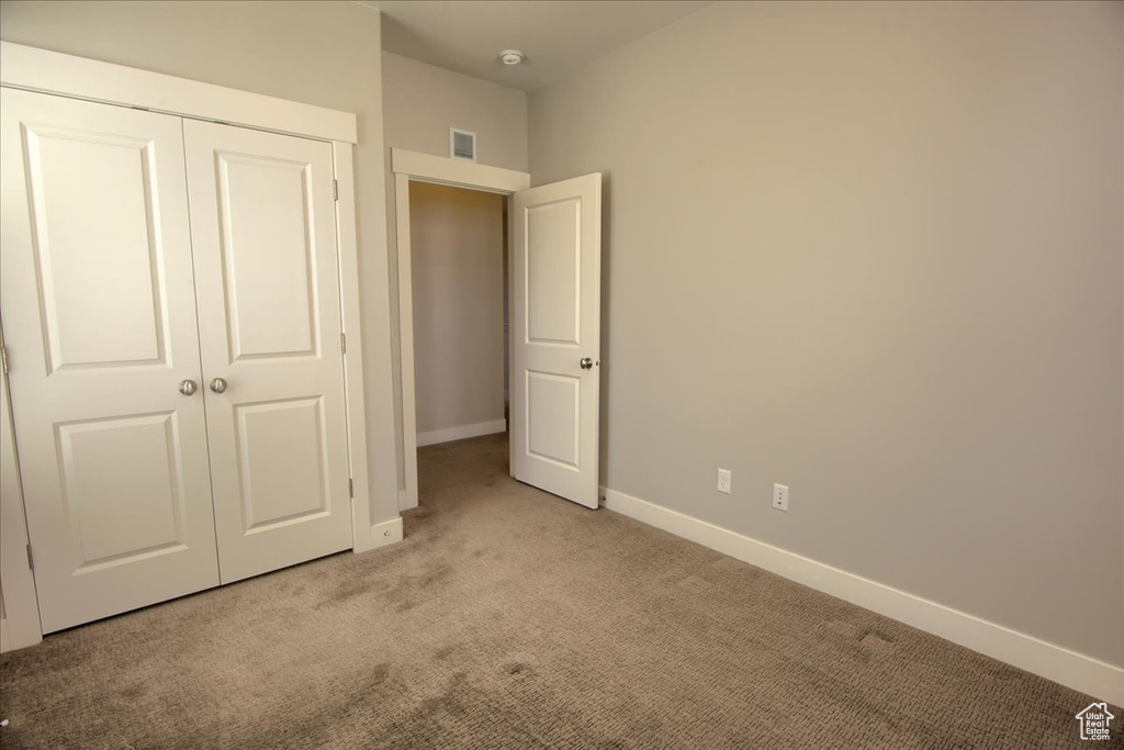 Unfurnished bedroom with light carpet, baseboards, and a closet