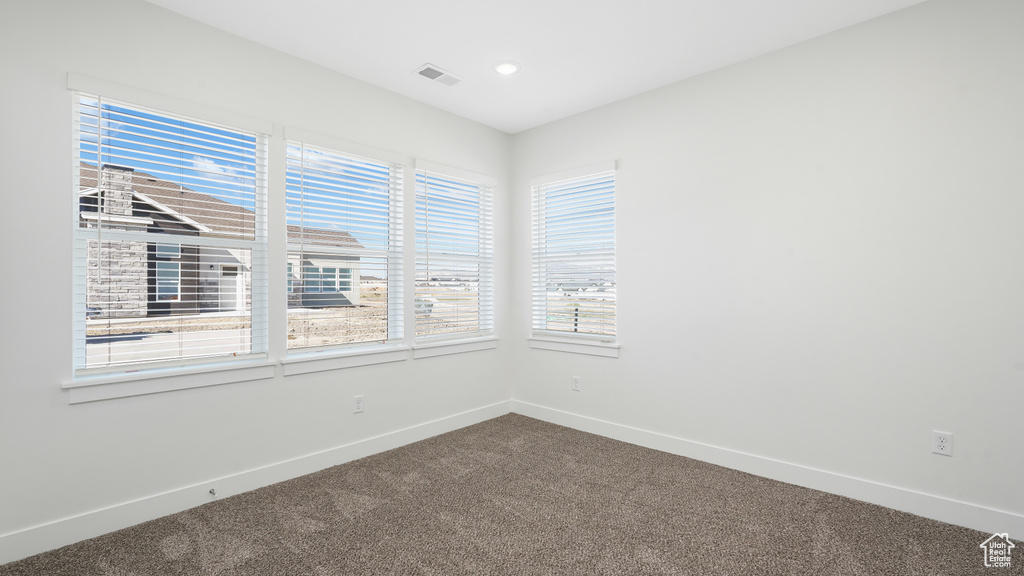 Empty room with dark carpet, baseboards, and recessed lighting