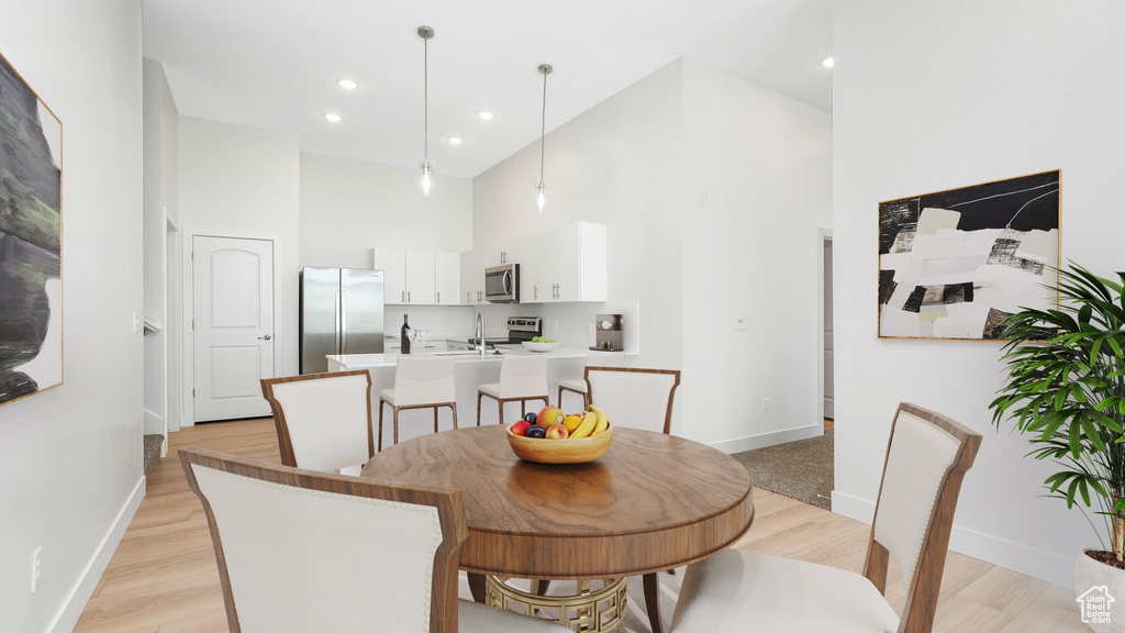 Dining room featuring a towering ceiling, baseboards, light wood-type flooring, and recessed lighting
