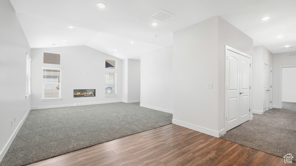 Unfurnished living room with wood finished floors, carpet, recessed lighting, baseboards, and a glass covered fireplace
