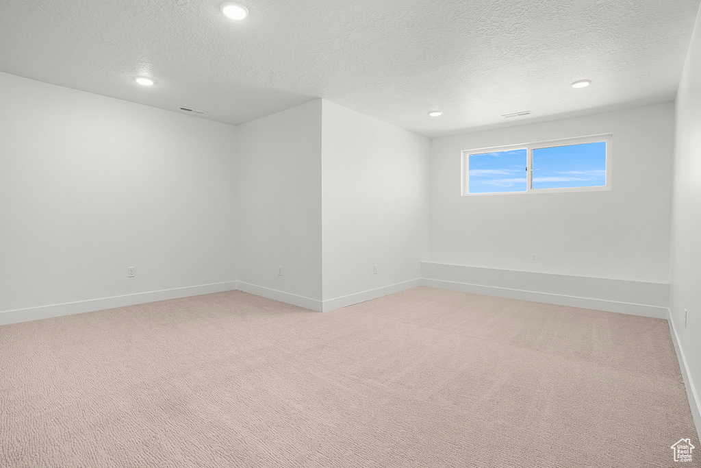 Unfurnished room with a textured ceiling, recessed lighting, light carpet, and baseboards