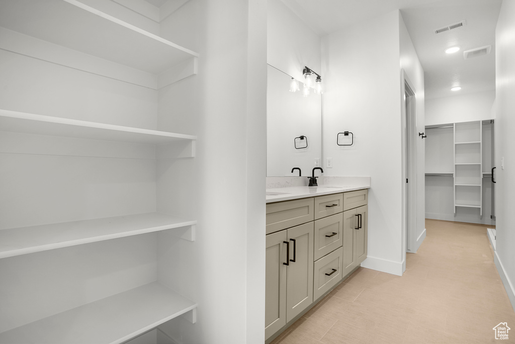 Bathroom with double vanity, a spacious closet, baseboards, and recessed lighting