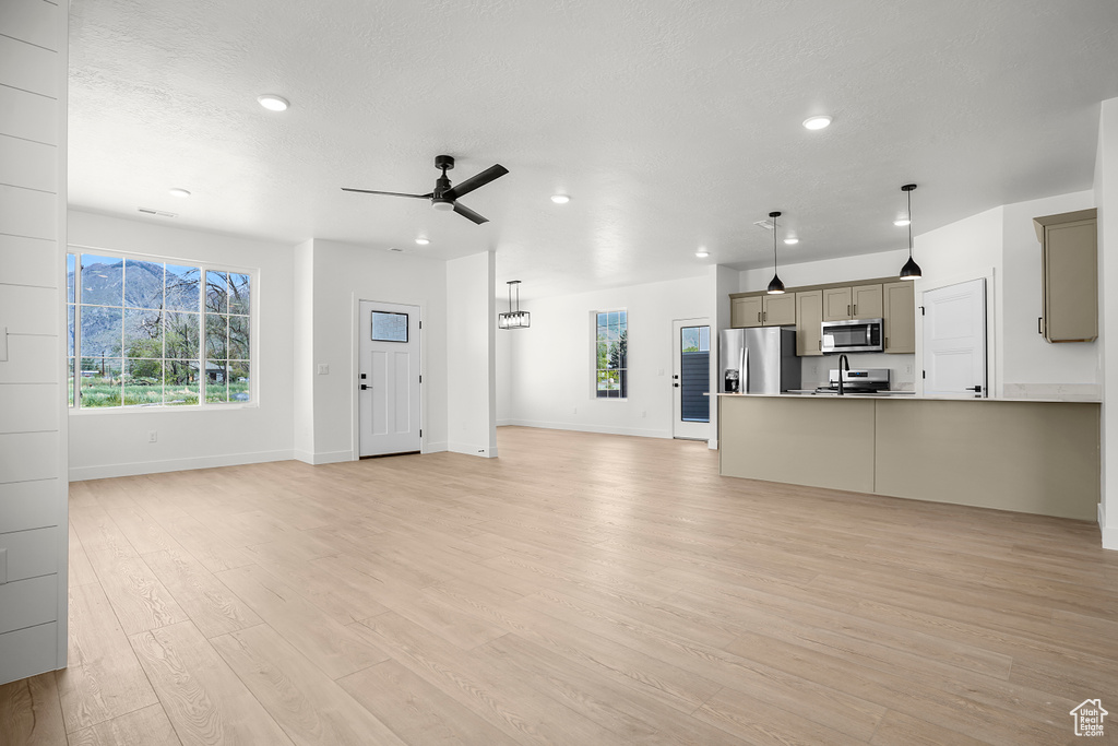 Unfurnished living room featuring recessed lighting, ceiling fan, light wood-type flooring, baseboards, and a textured ceiling