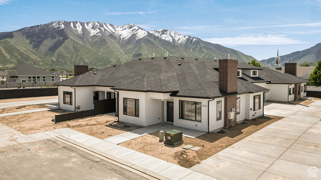 Rear view of property featuring a chimney, roof with shingles, a patio area, and a mountain view