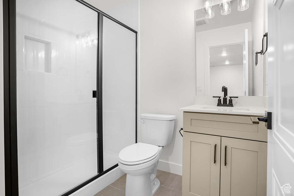 Bathroom with toilet, vanity, a stall shower, tile patterned floors, and baseboards