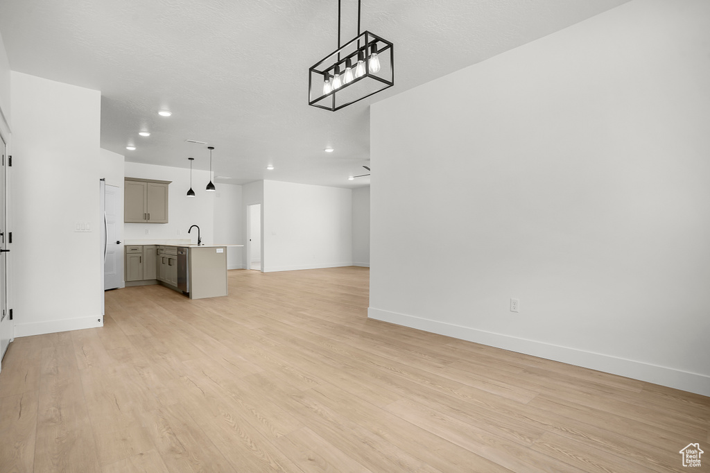 Unfurnished living room with a sink, baseboards, light wood-style flooring, and recessed lighting