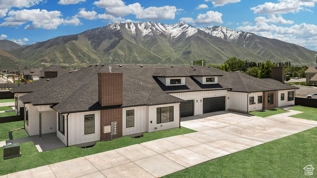 View of front of property featuring roof with shingles, board and batten siding, driveway, and a mountain view