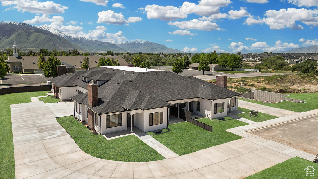 View of front of property with a chimney, a residential view, a mountain view, roof with shingles, and driveway