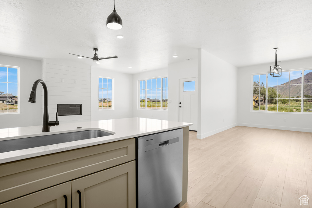 Kitchen featuring dishwasher, a sink, light wood-style flooring, gray cabinetry, and baseboards