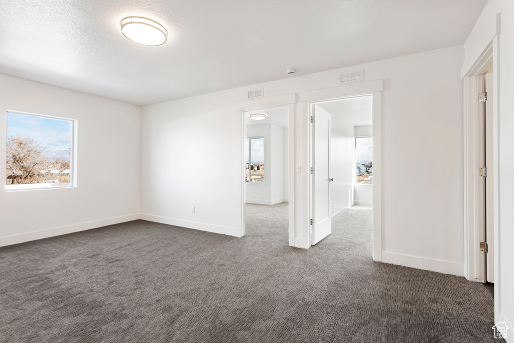 Empty room featuring dark colored carpet and baseboards