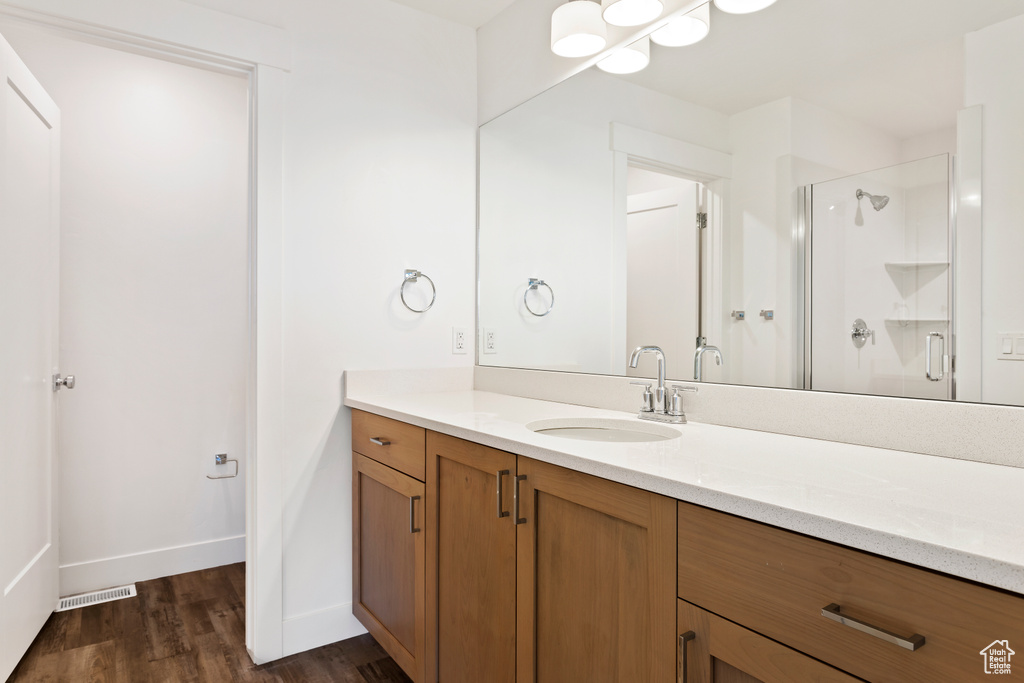 Bathroom featuring a shower stall, baseboards, wood finished floors, and vanity