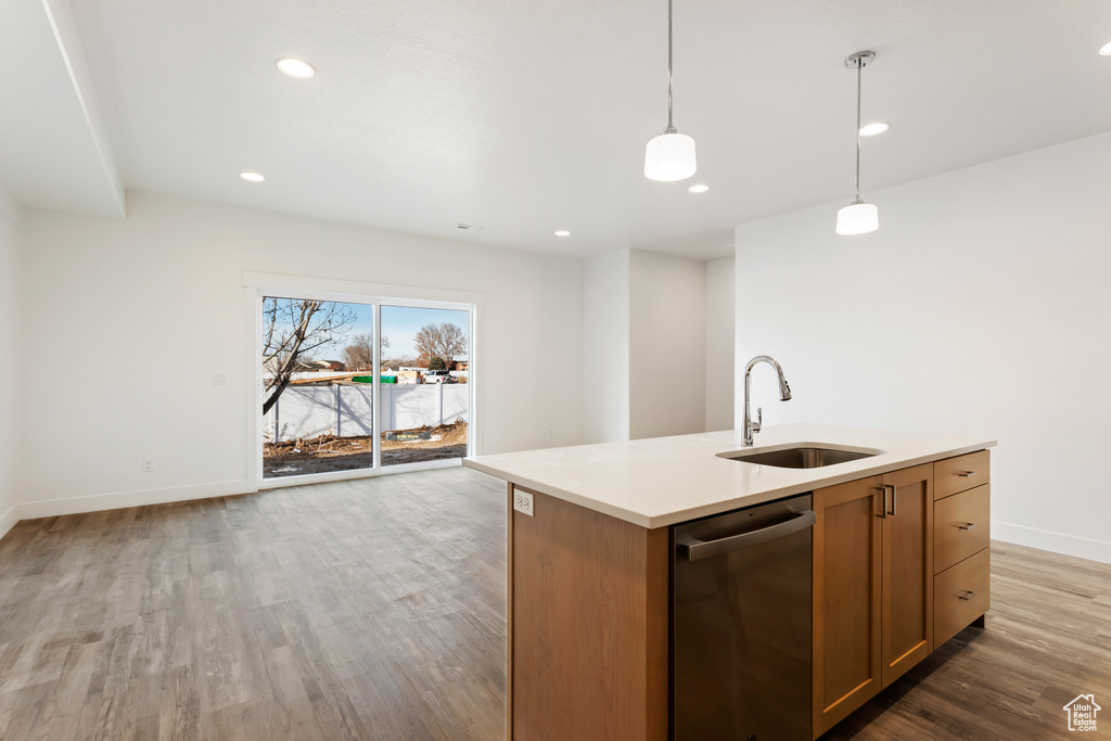 Kitchen featuring a sink, dishwasher, open floor plan, light wood-type flooring, and baseboards
