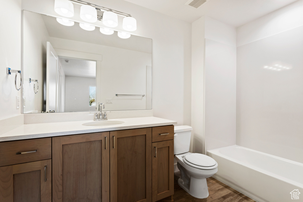 Full bath featuring vanity, toilet, and wood finished floors