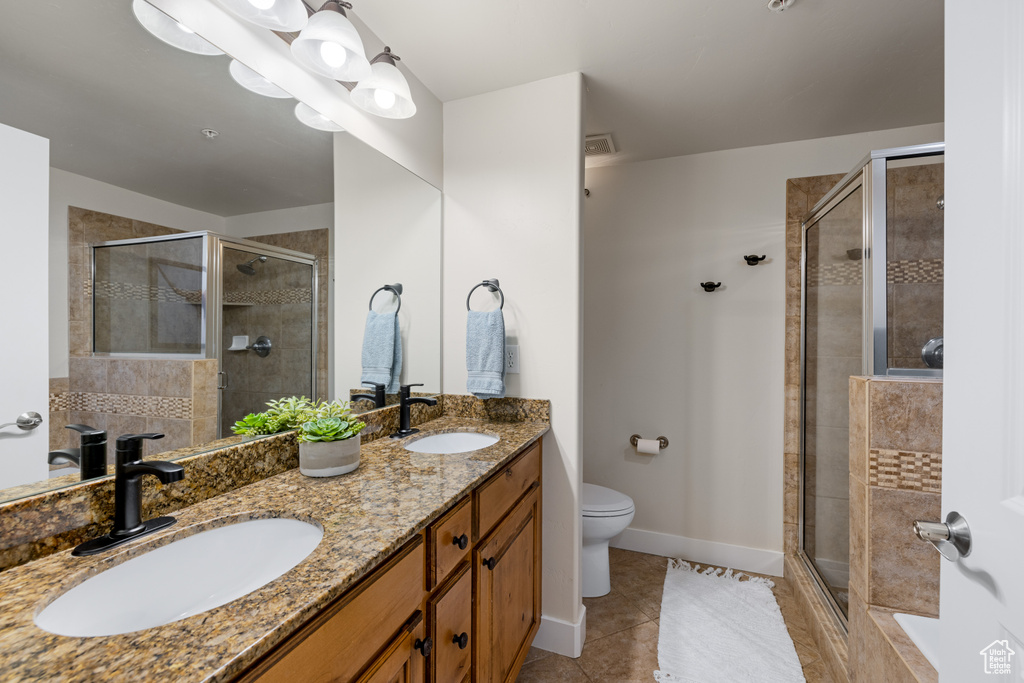 Full bath with a stall shower, tile patterned flooring, toilet, and double vanity