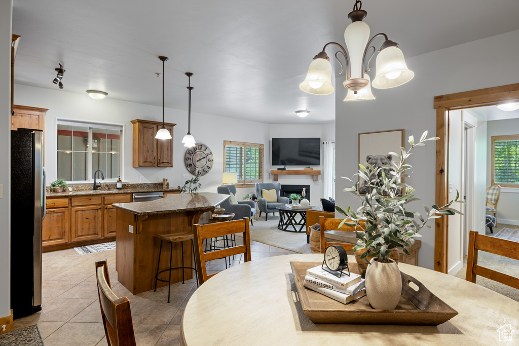 Dining room with light tile patterned flooring, a fireplace, and a chandelier