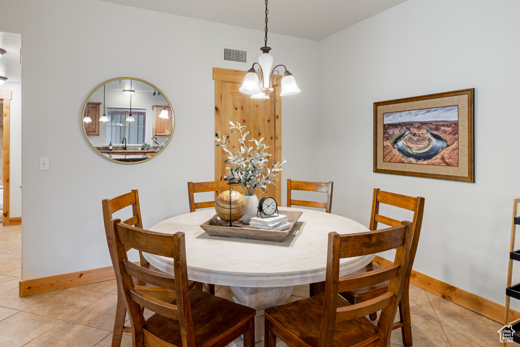 Dining space featuring light tile patterned floors, a chandelier, and baseboards