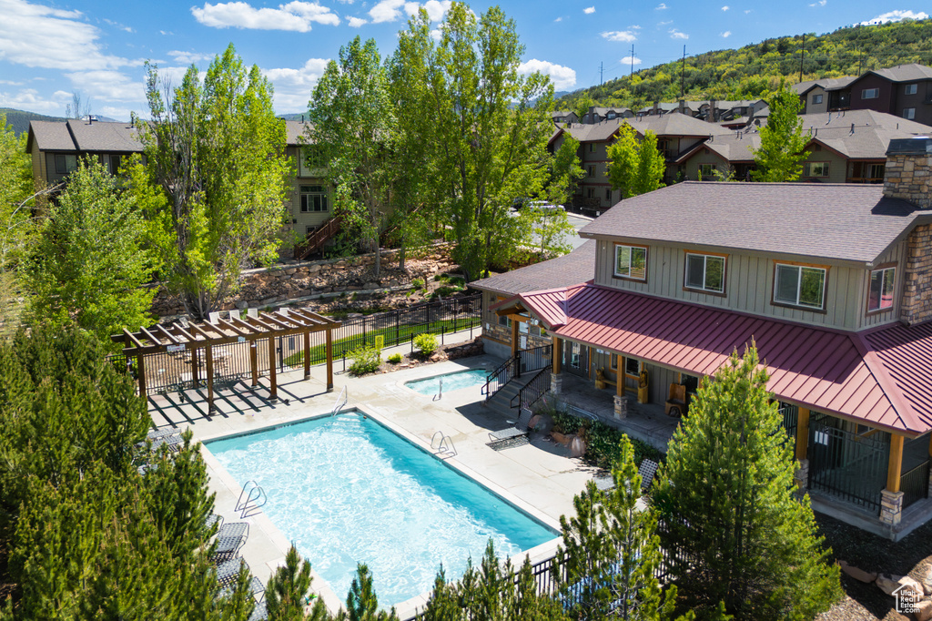 Community pool with a pergola, a patio area, and a residential view