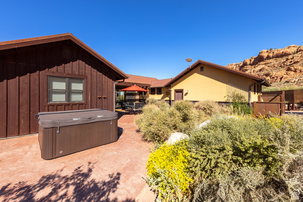 View of side of home with a patio and a hot tub