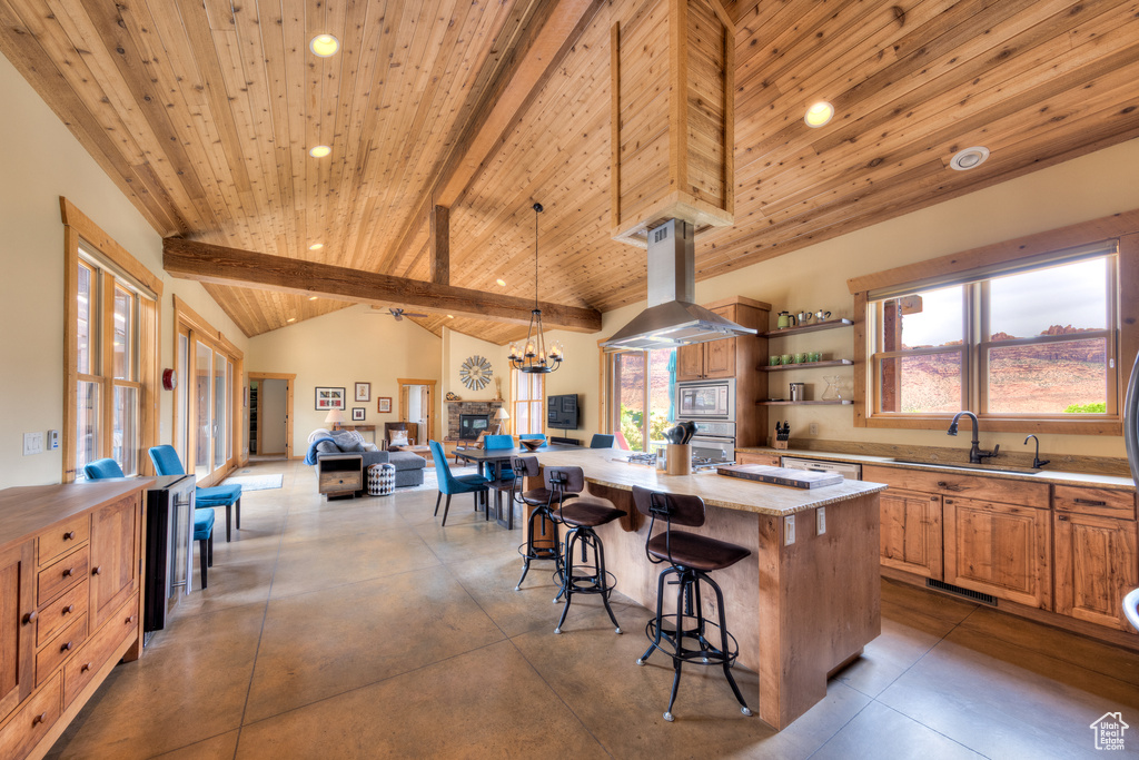 Kitchen featuring appliances with stainless steel finishes, island range hood, wooden ceiling with exposed beams, recessed lighting, and a sink