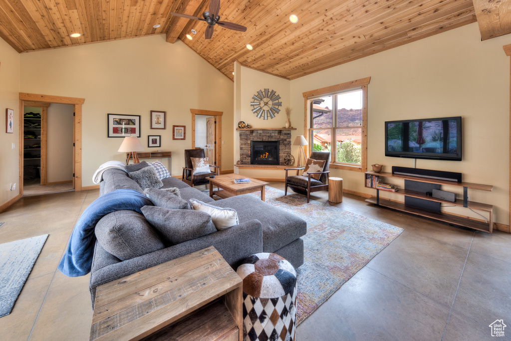 Living area featuring concrete floors, wood ceiling with exposed beams, baseboards, a fireplace, and ceiling fan