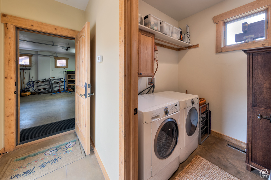 Laundry room featuring cabinet space, washing machine and dryer, healthy amount of natural light, and baseboards