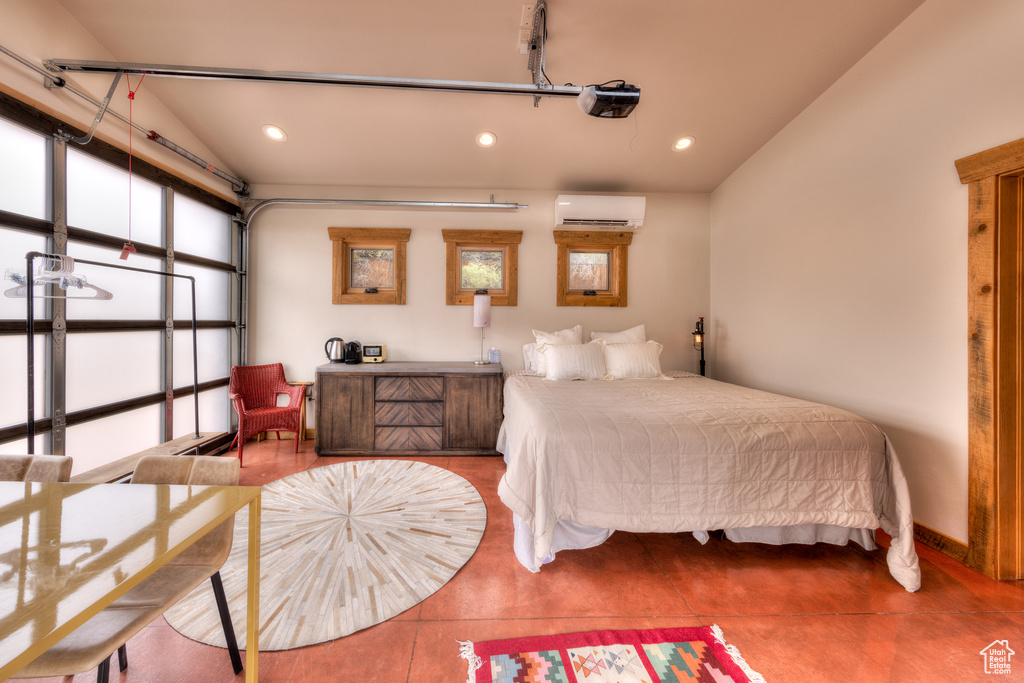 Bedroom featuring a wall unit AC, recessed lighting, vaulted ceiling, and a garage