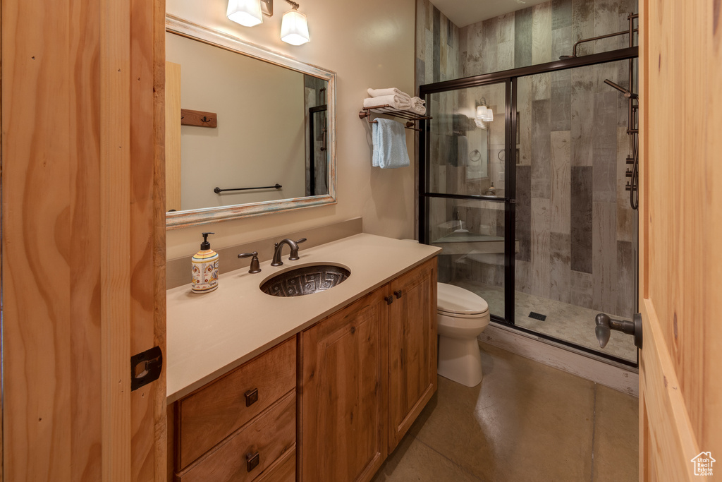 Bathroom featuring toilet, vanity, and a stall shower