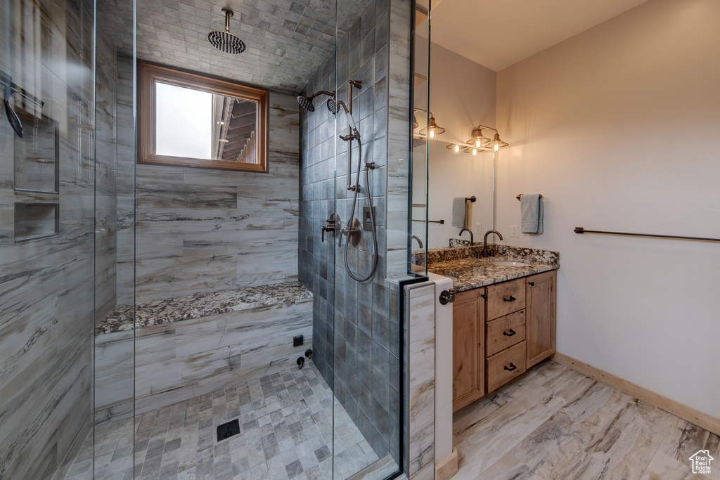 Bathroom featuring a tile shower, vanity, and baseboards