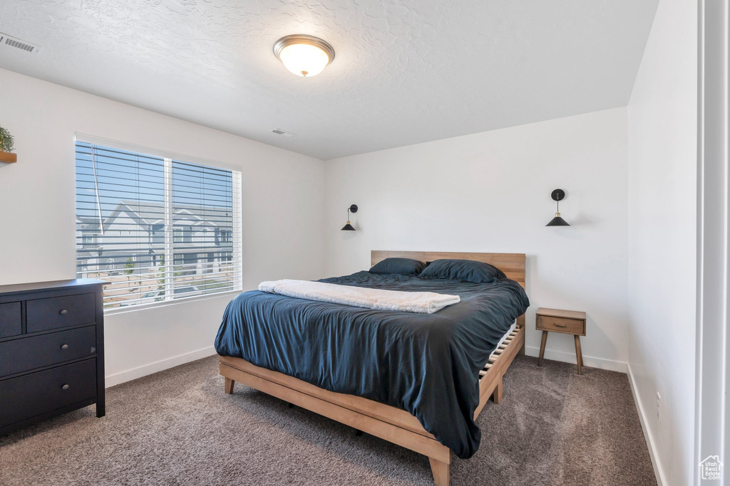 Bedroom with carpet flooring, baseboards, and a textured ceiling
