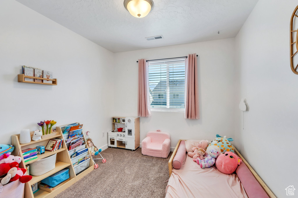 Carpeted bedroom featuring baseboards and a textured ceiling