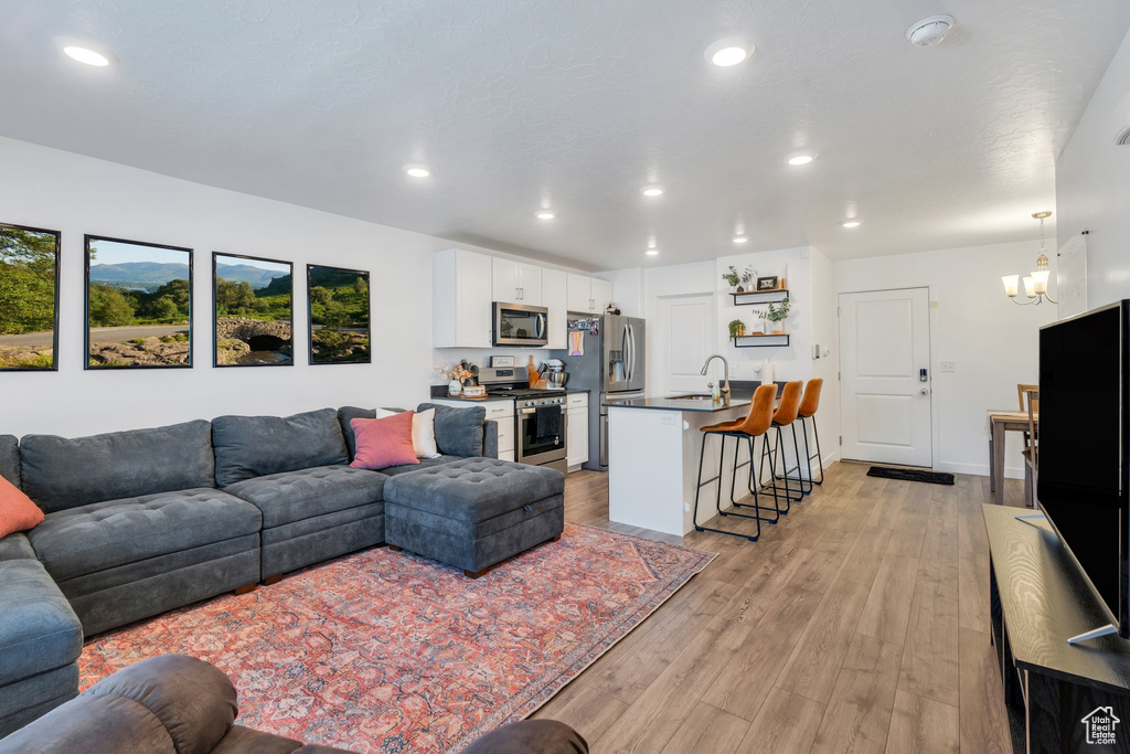 Living room with light wood finished floors, recessed lighting, and a chandelier