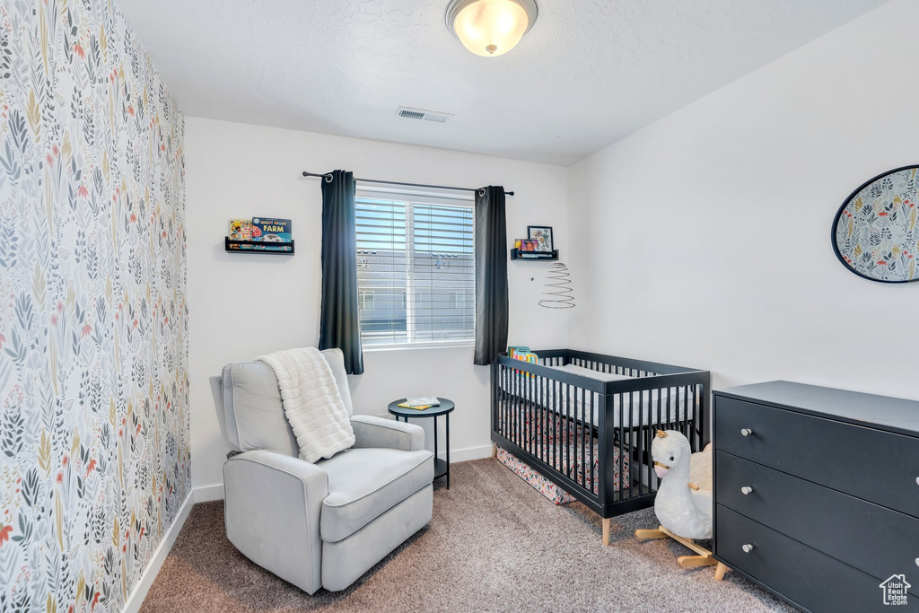 Carpeted bedroom featuring a crib and baseboards