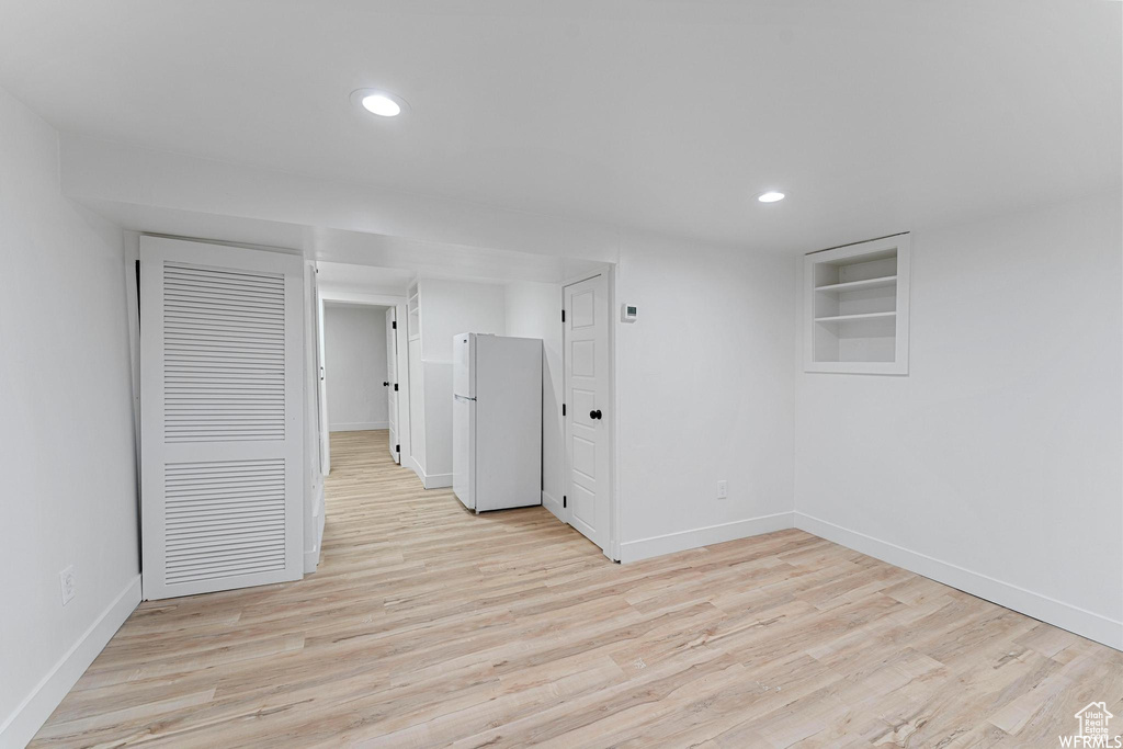 Basement featuring freestanding refrigerator, baseboards, light wood-style flooring, recessed lighting, and built in features