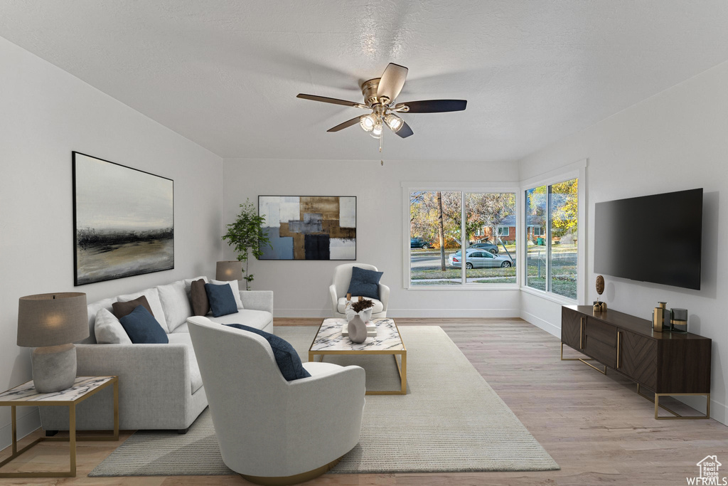 Living area with a ceiling fan, baseboards, and light wood-type flooring