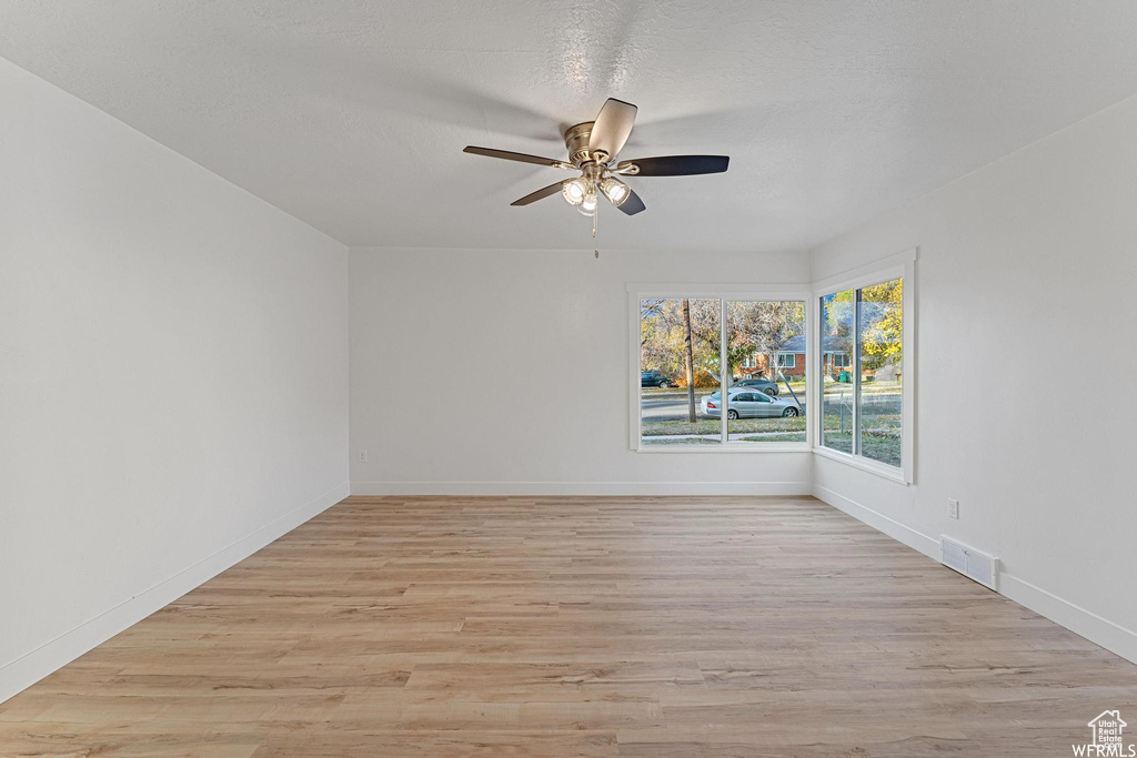 Unfurnished room featuring ceiling fan, light wood-style flooring, and baseboards