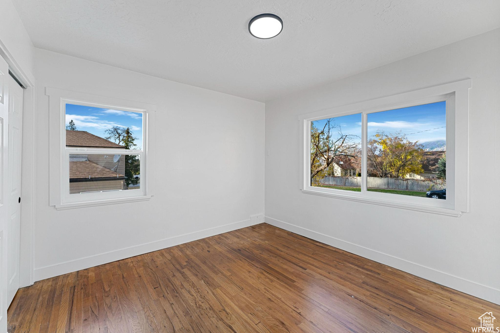 Unfurnished bedroom featuring baseboards, multiple windows, and dark wood-style flooring