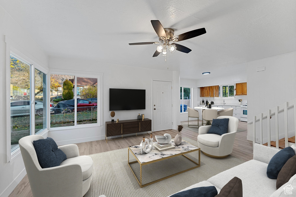Living area with light wood-type flooring, baseboards, and a ceiling fan