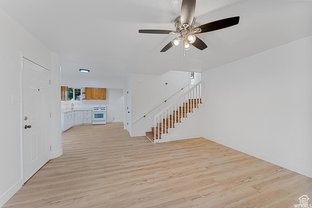 Entrance foyer featuring a ceiling fan, light wood-type flooring, stairs, and baseboards