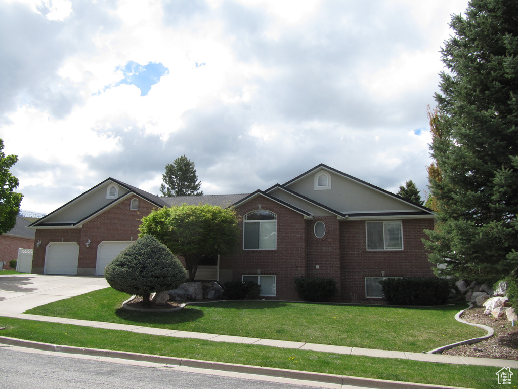 Single story home featuring brick siding, concrete driveway, an attached garage, and a front lawn