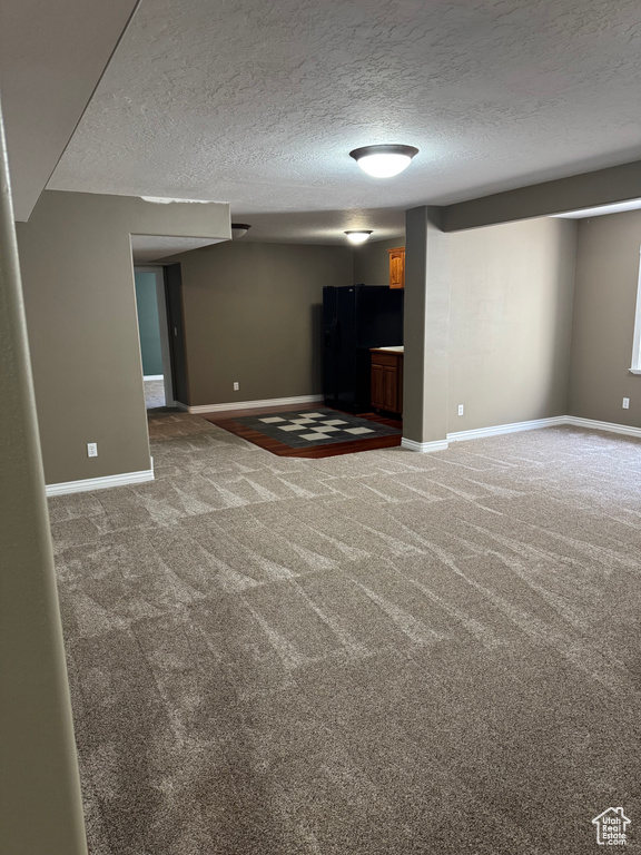 Unfurnished living room with carpet floors, baseboards, and a textured ceiling