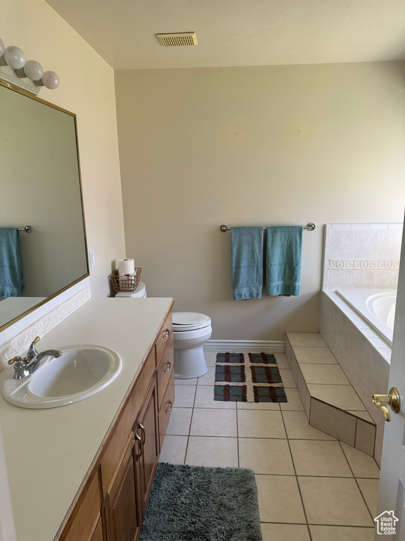 Bathroom featuring a bath, vanity, tile patterned floors, and toilet