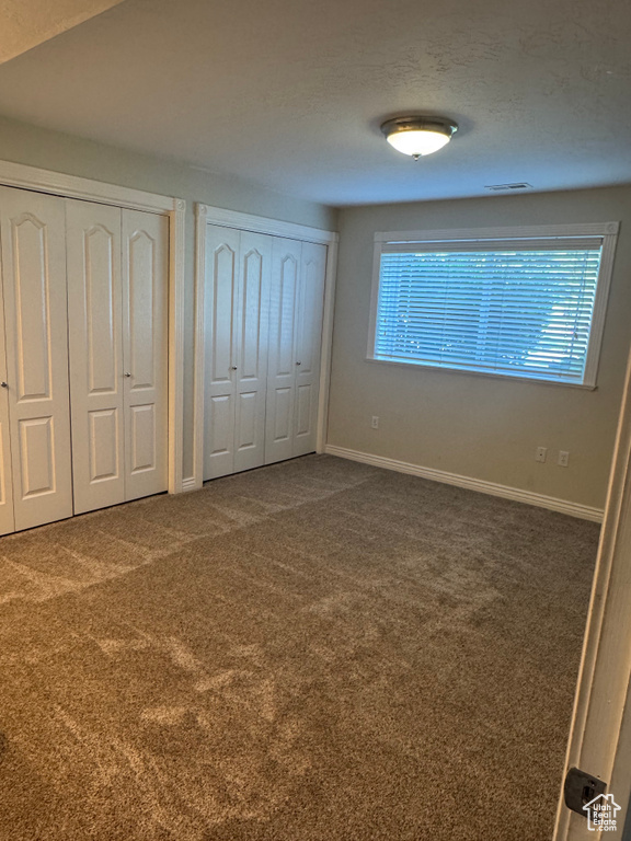 Unfurnished bedroom with multiple closets, carpet floors, and baseboards