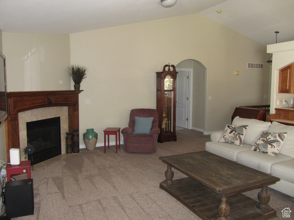 Carpeted living area with vaulted ceiling, a high end fireplace, arched walkways, and baseboards