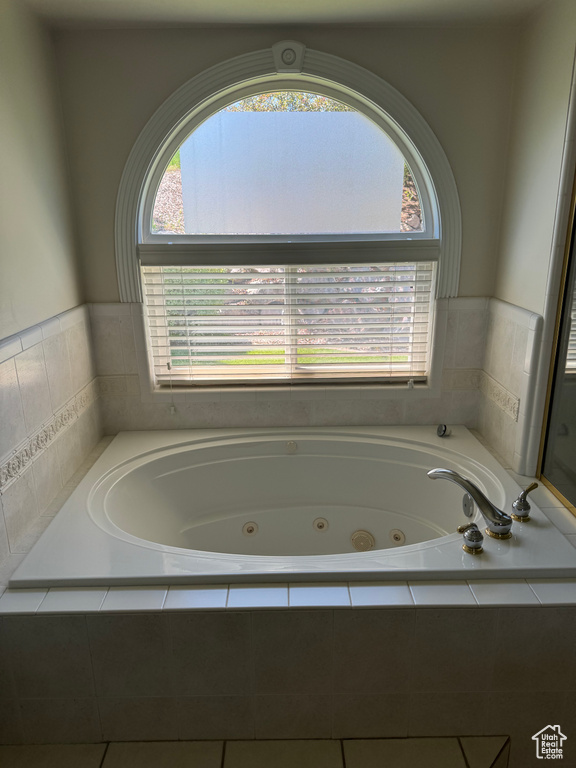 Full bathroom featuring healthy amount of natural light and a tub with jets