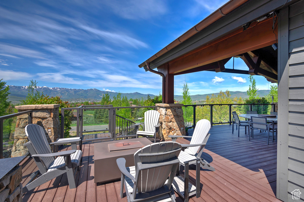 Wooden deck with a mountain view, an outdoor fire pit, and outdoor dining area