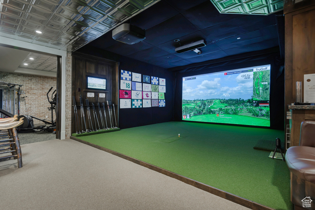 Rec room with golf simulator, brick wall, and carpet floors