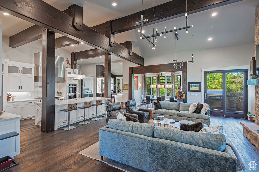 Living room with beam ceiling, dark wood-type flooring, recessed lighting, and a towering ceiling