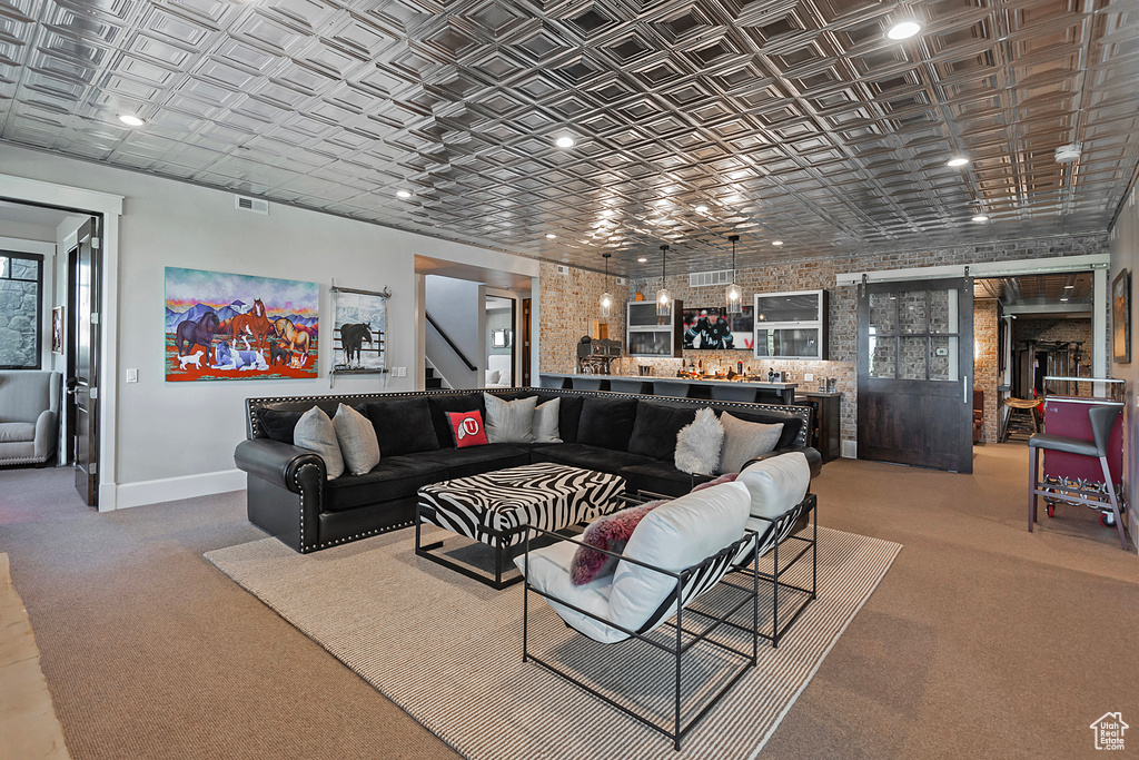 Living area featuring an ornate ceiling, baseboards, carpet, a barn door, and a bar