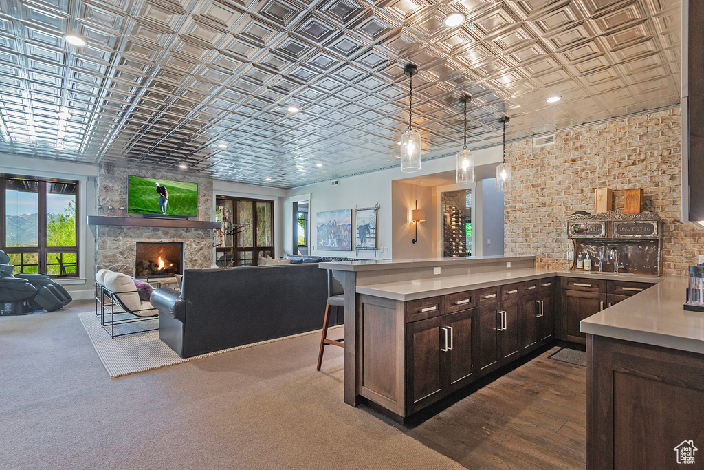 Kitchen featuring an ornate ceiling, light countertops, dark brown cabinets, a fireplace, and decorative light fixtures