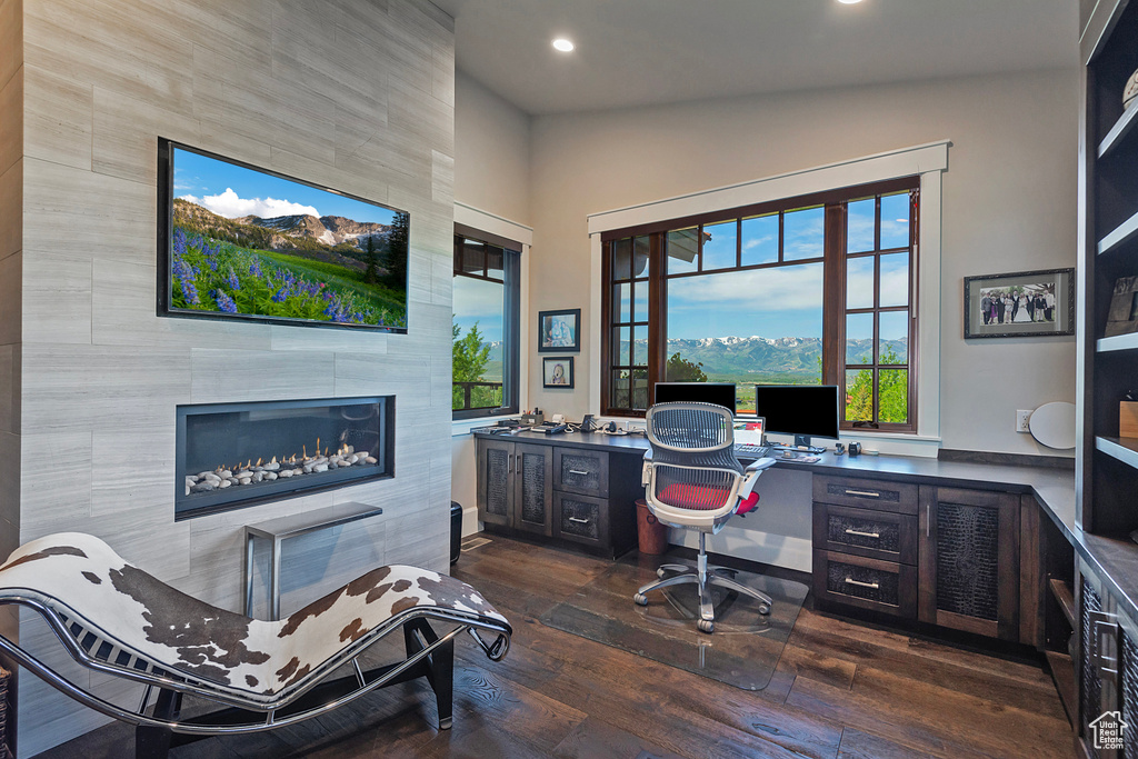 Office with dark wood finished floors, recessed lighting, a tiled fireplace, and built in study area